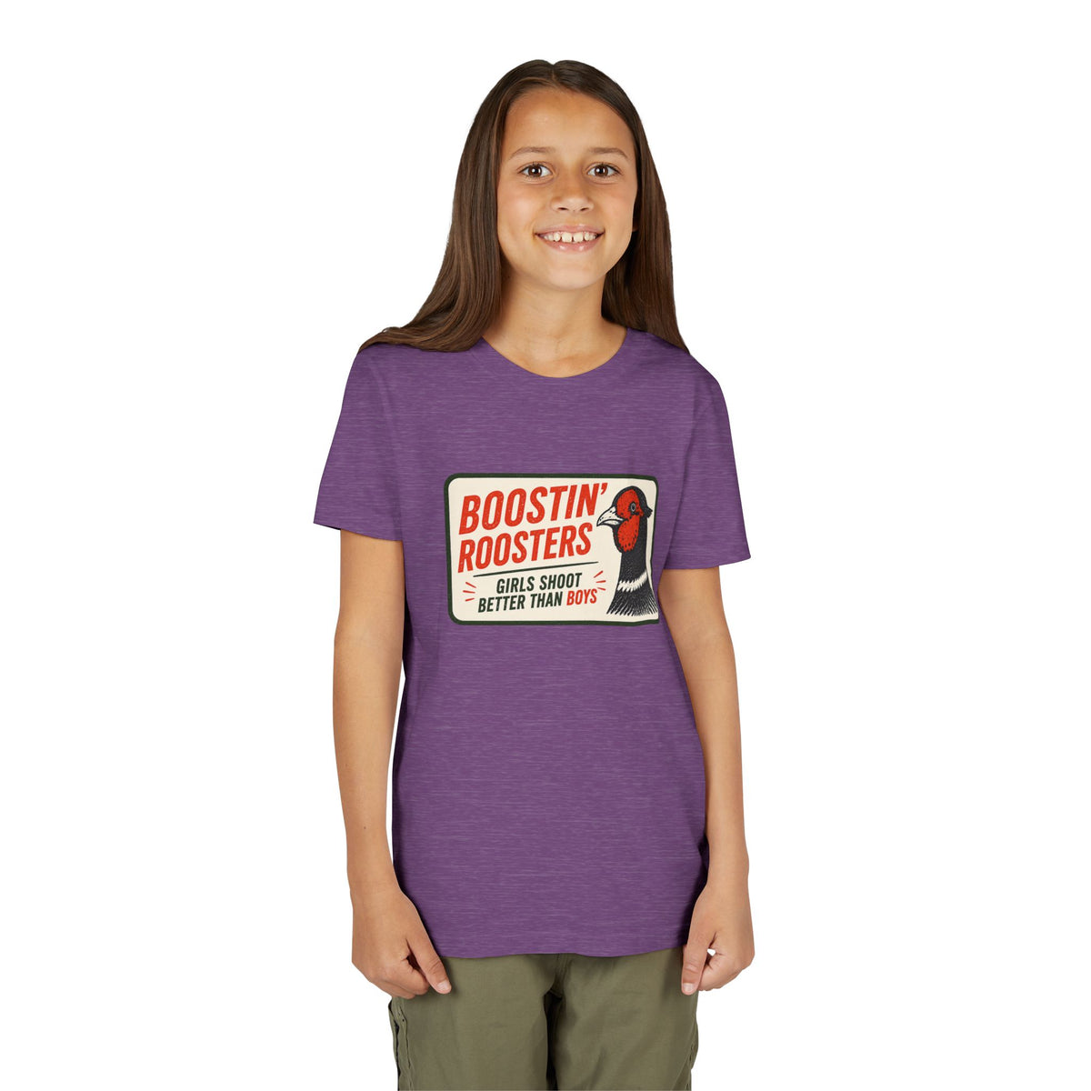 A young girl with long brown hair stands against a plain white background wearing a heather purple t-shirt with a retro-style graphic that reads 'BOOSTIN' ROOSTERS' and shows a rooster illustration. She is also wearing olive green pants.