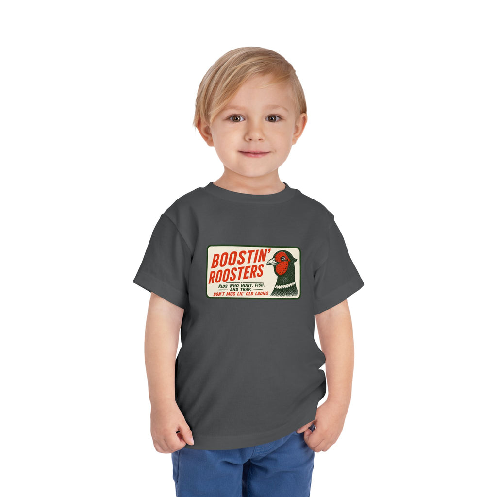 A young child wearing a dark gray t-shirt with a vintage-style 'Boostin' Roosters' graphic on the chest, paired with blue pants, standing against a plain white background.