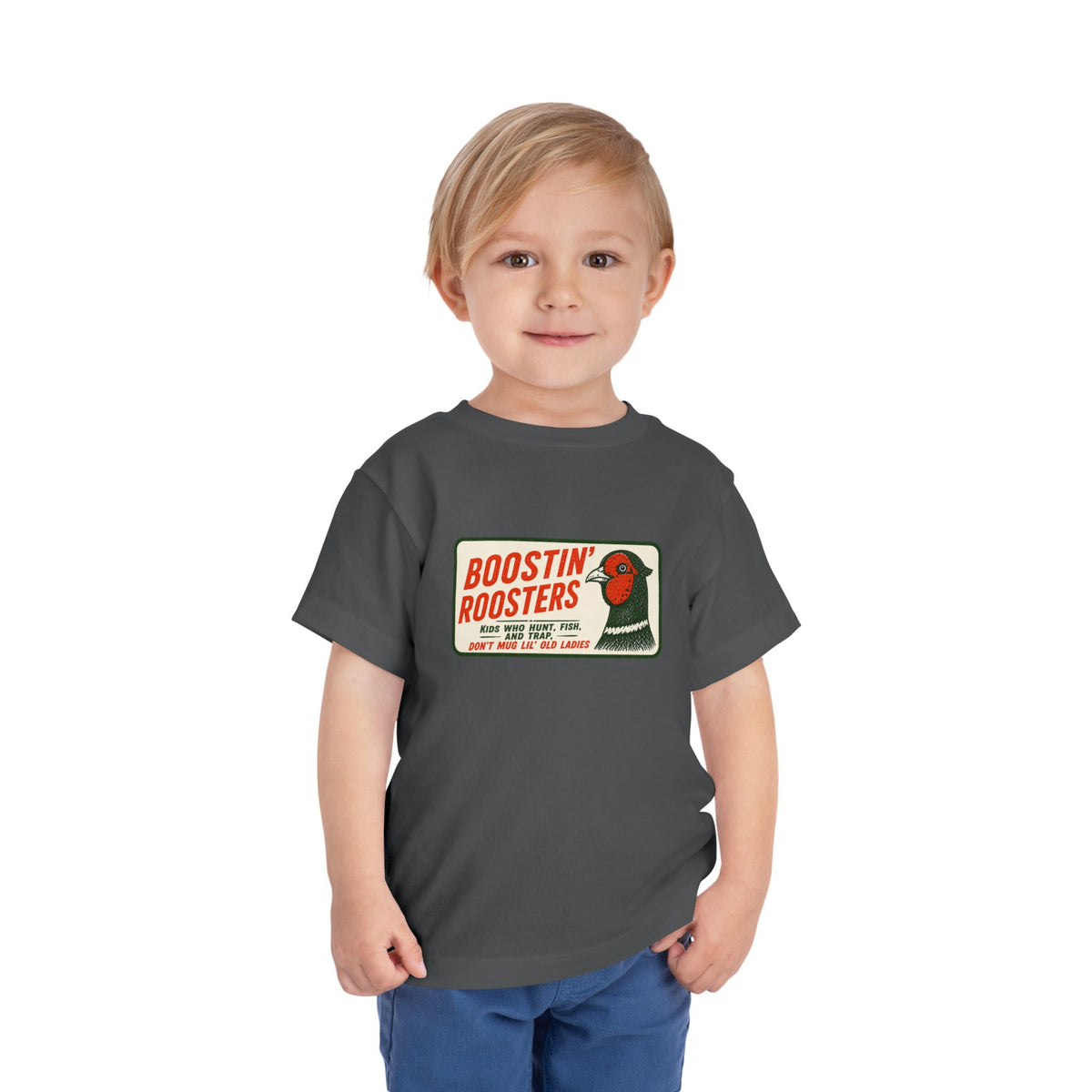 A young child wearing a dark gray t-shirt with a vintage-style 'Boostin' Roosters' graphic on the chest, paired with blue pants, standing against a plain white background.